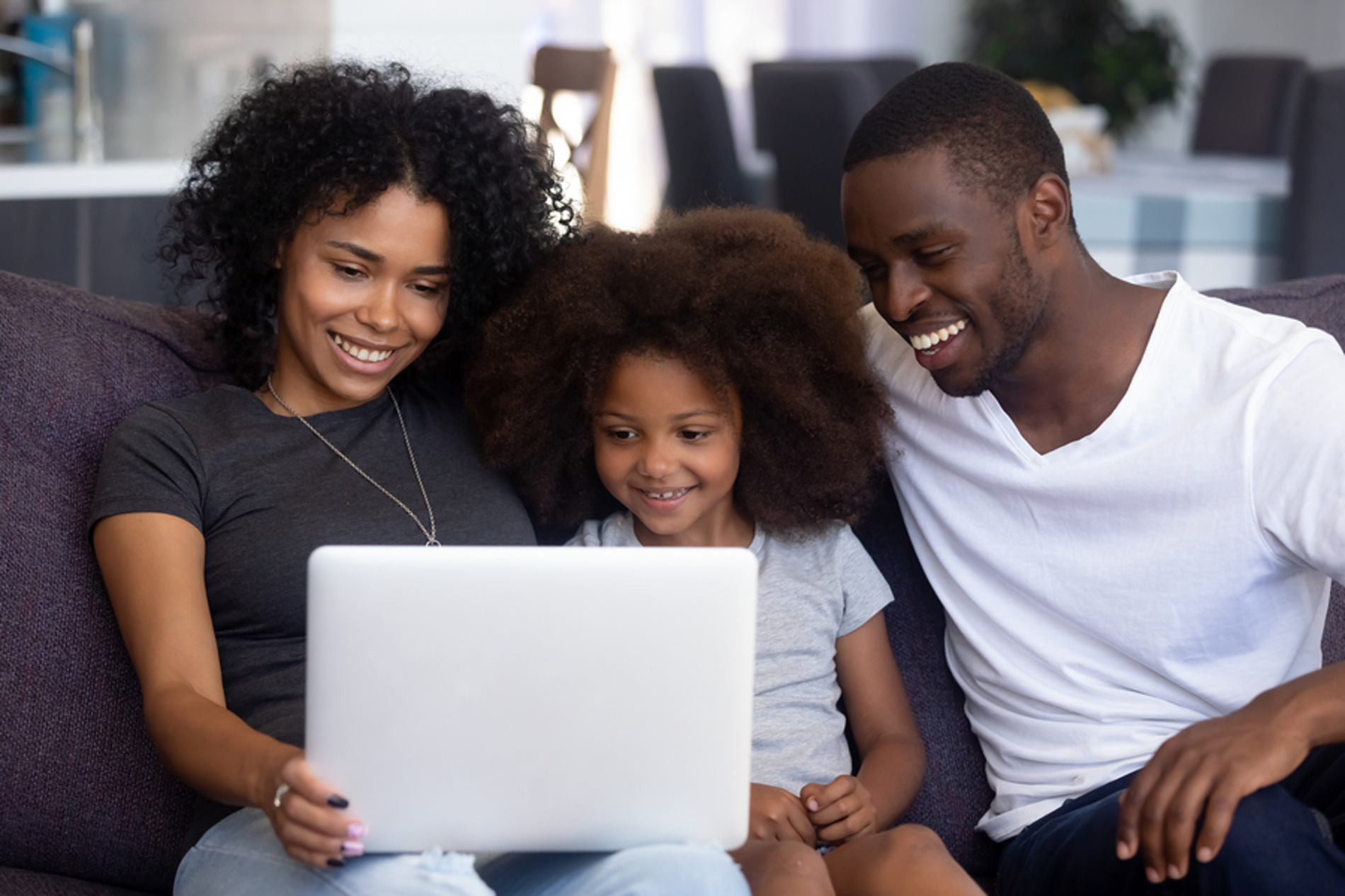Failing sitting on a couch looking at a laptop together smiling.